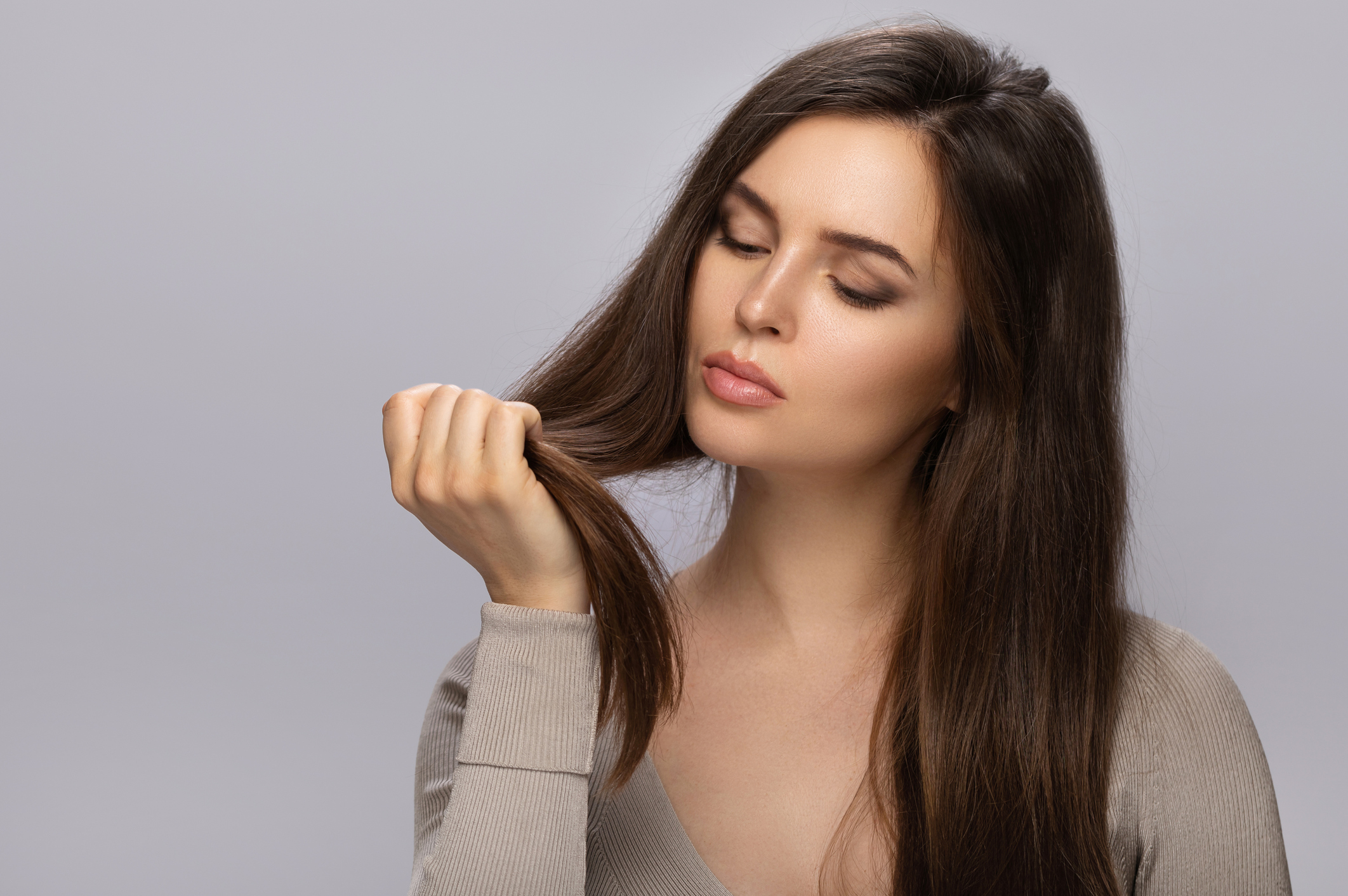 Mulher segurando o próprio cabelo e observando se ele está com frizz.